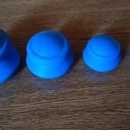 Cztery silikonowe bańki do terapii, różnej wielkości, ułożone w rzędzie na drewnianym blacie.