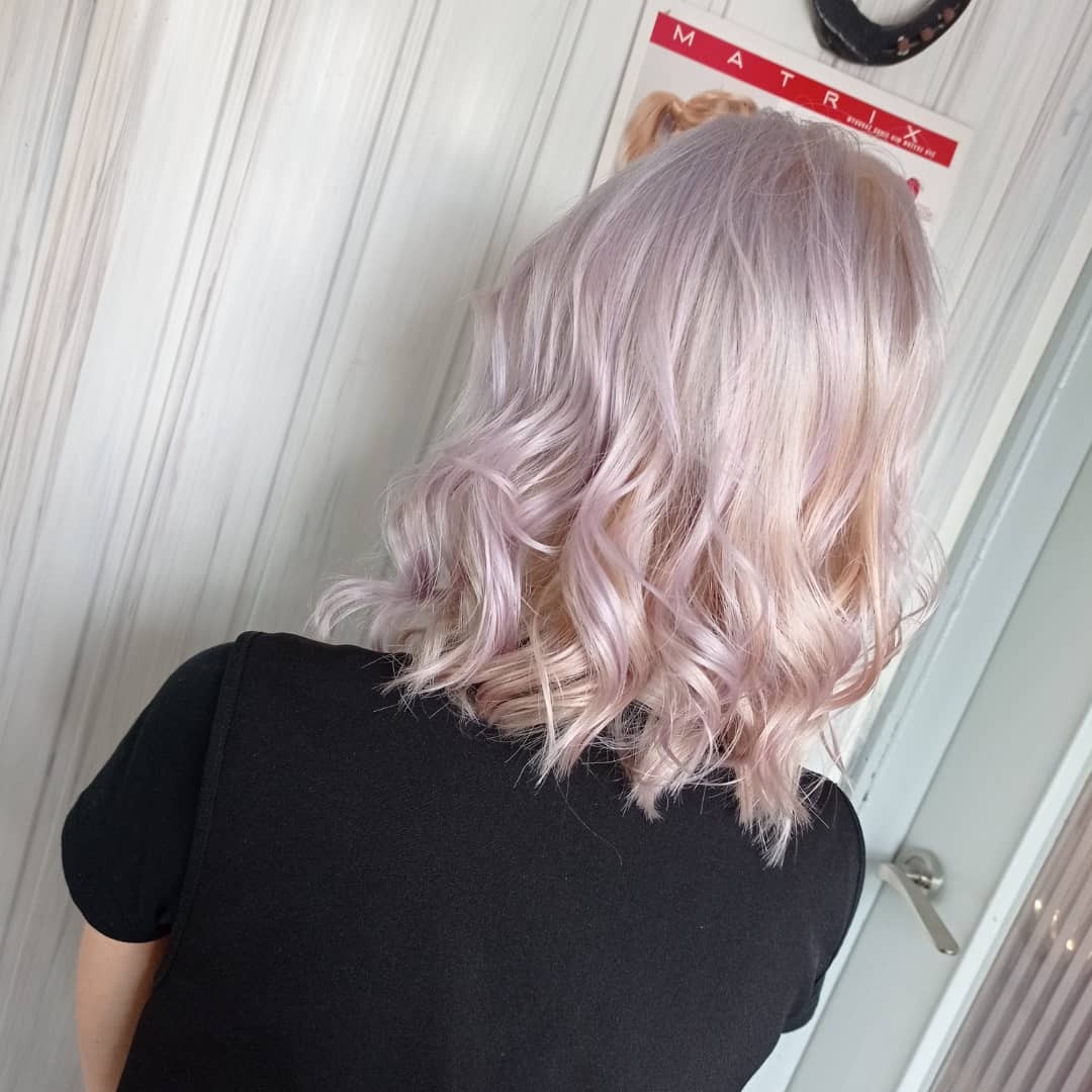 Fryzura bob z falami w odcieniach liliowego blondu, widok z tyłu, na ścianie plakat marki Matrix.