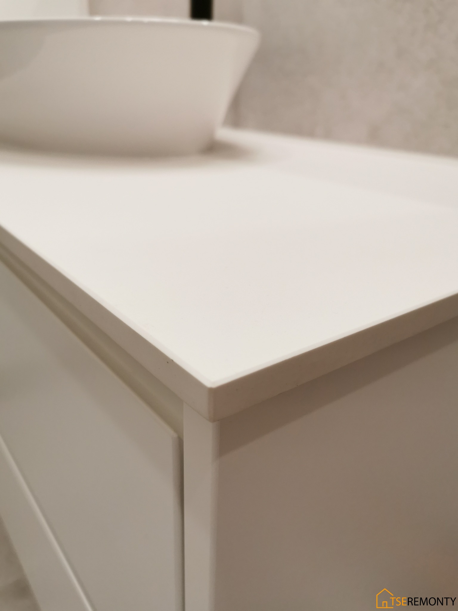 Biała umywalka nablatowa na szafce z blatem, minimalistyczny design, neutralne tło ściany.