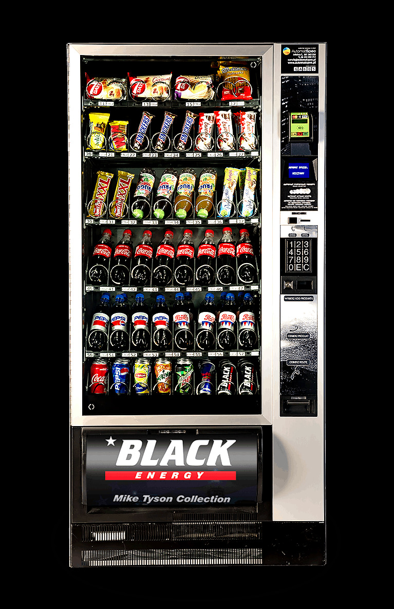 Automat vendingowy z przekąskami i napojami, widoczne batony Snickers, Prince Polo XXL, napoje Coca-Cola, Pepsi, Lipton Ice Tea oraz energetyki Black Energy sygnowane przez Mike'a Tysona.