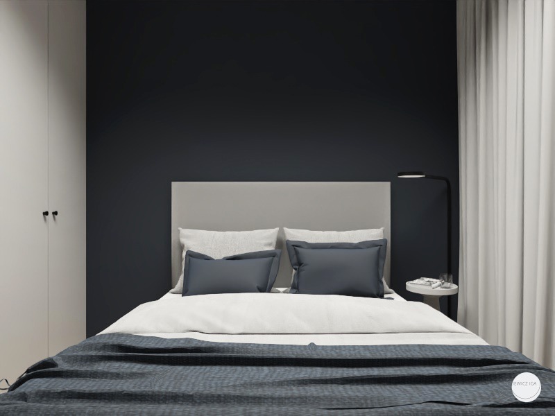 Minimalistyczna sypialnia z ciemnogranatową ścianą, szarą tapicerowaną ramą łóżka, białą pościelą i pledem w odcieniach szarości, uzupełniona lampką nocną na okrągłym stoliku i białymi zasłonami.