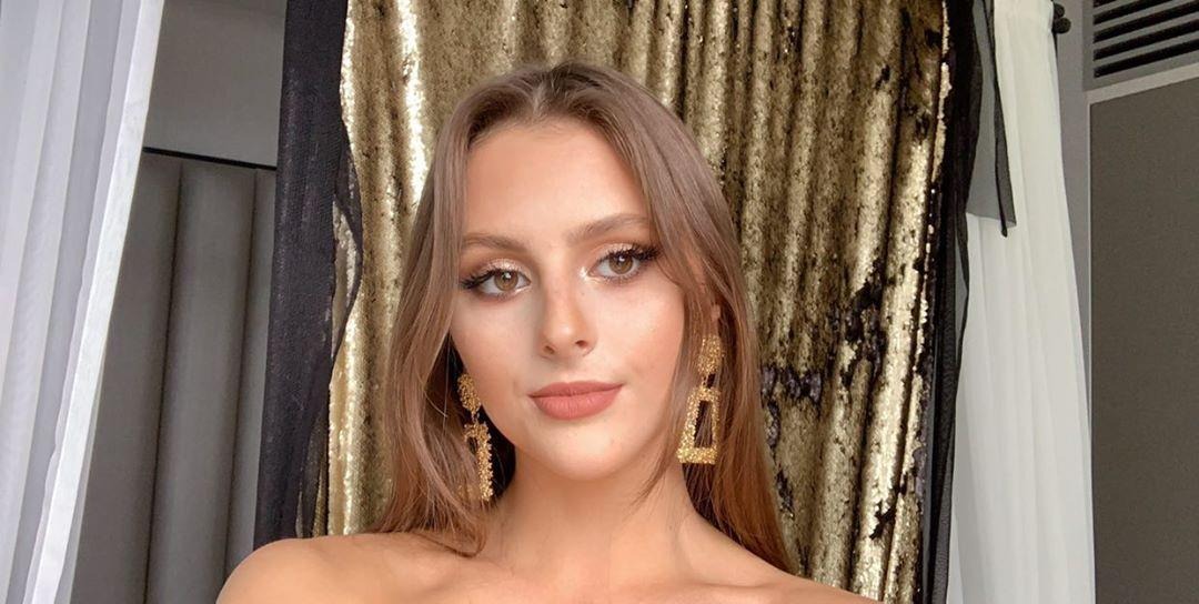 Portret kobiety z delikatnym, rozświetlonym makijażem, złotymi kolczykami i tłem z cekinowej tkaniny.