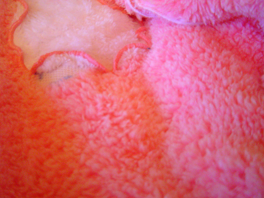 Fragment szlafroka dziecięcego z miękkiego, różowego softu z dekoracyjnym obszyciem w jaśniejszym odcieniu różu.