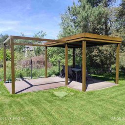 NA TARASIE Sp. z o.o. - Nowoczesna pergola z drewna na tarasie, otoczona zielonym trawnikiem. Widoczne krzesła i stół pod zadaszeniem, tworzące przestrzeń do relaksu na świeżym powietrzu.