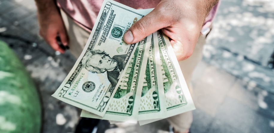 Dłoń trzymająca kilka banknotów dwudziestodolarowych w Krakowie, z widocznymi detalami nominałów i faktury papieru.