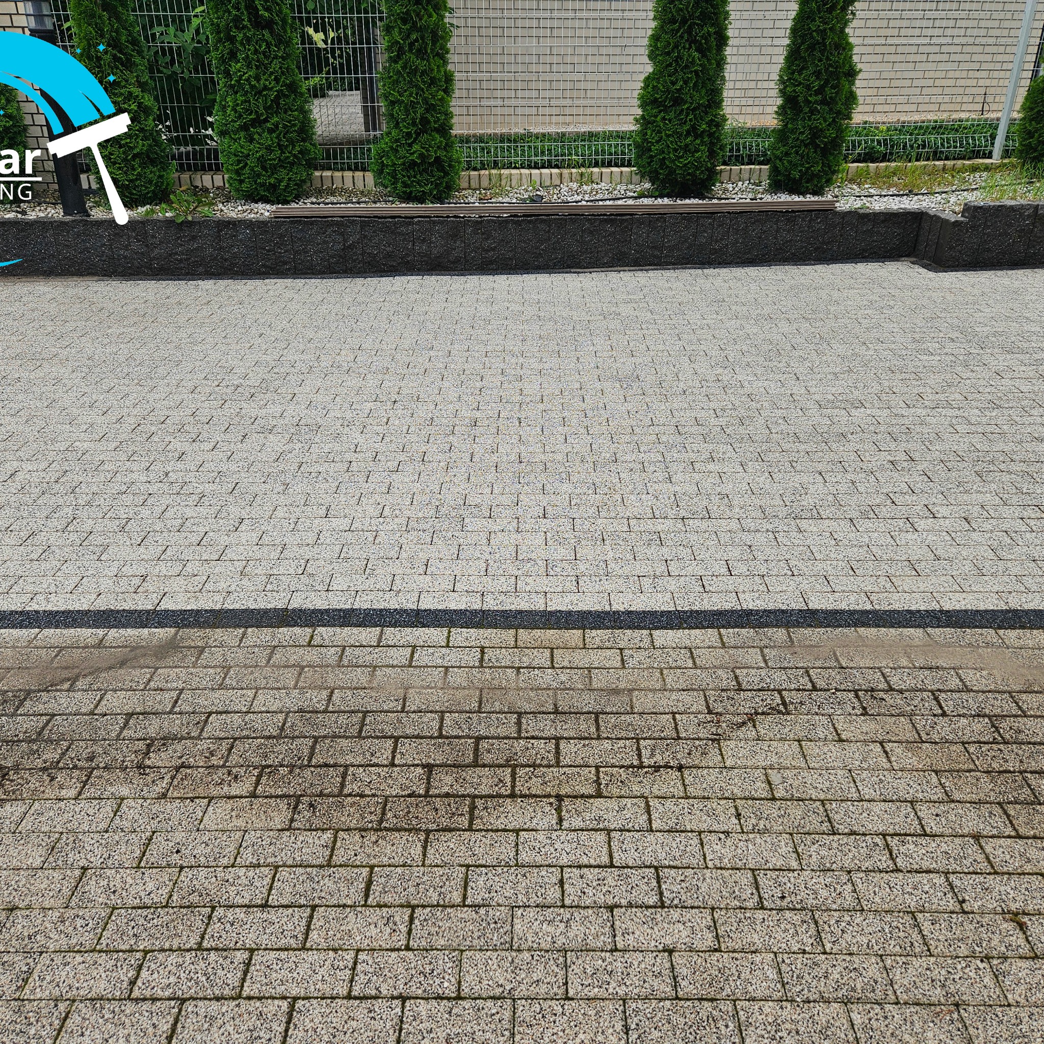 Częściowo wyczyszczona kostka brukowa w odcieniach szarości, z widoczną różnicą w kolorze między umytą a nieumytą powierzchnią, na tle żywopłotu z tuj.