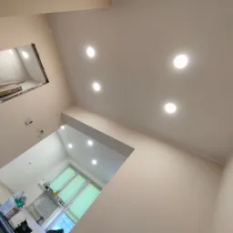 Wykończone wnętrze z sufitem podwieszanym z oświetleniem punktowym, widoczne przygotowania do montażu płyty karton gips w sąsiednim pomieszczeniu.