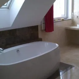 Nowoczesna łazienka na poddaszu z owalną wanną, jasnymi płytkami i dwoma umywalkami nablatowymi, oświetlona przez okno dachowe.