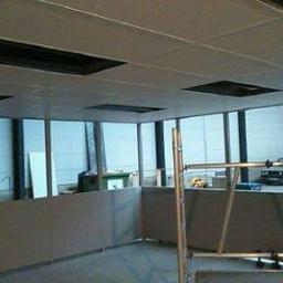 Remonty i dachy - Montaż sufitu podwieszanego w biurze z widocznymi oknami, rusztowaniem i elementami instalacji.