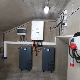 WOLTBERG Roman Mika - Instalacja fotowoltaiczna z magazynem energii ECOBSS w Radlinie. Widoczne falownik hybrydowy DEYE, rozdzielnica, baterie i okablowanie. Nowoczesne rozwiązanie OZE.