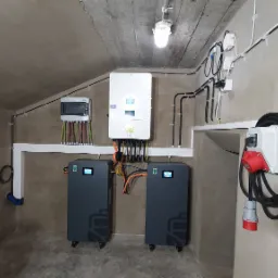 Instalacja fotowoltaiczna z magazynem energii ECOBSS w Radlinie. Widoczne falownik hybrydowy DEYE, rozdzielnica, baterie i okablowanie. Nowoczesne rozwiązanie OZE.