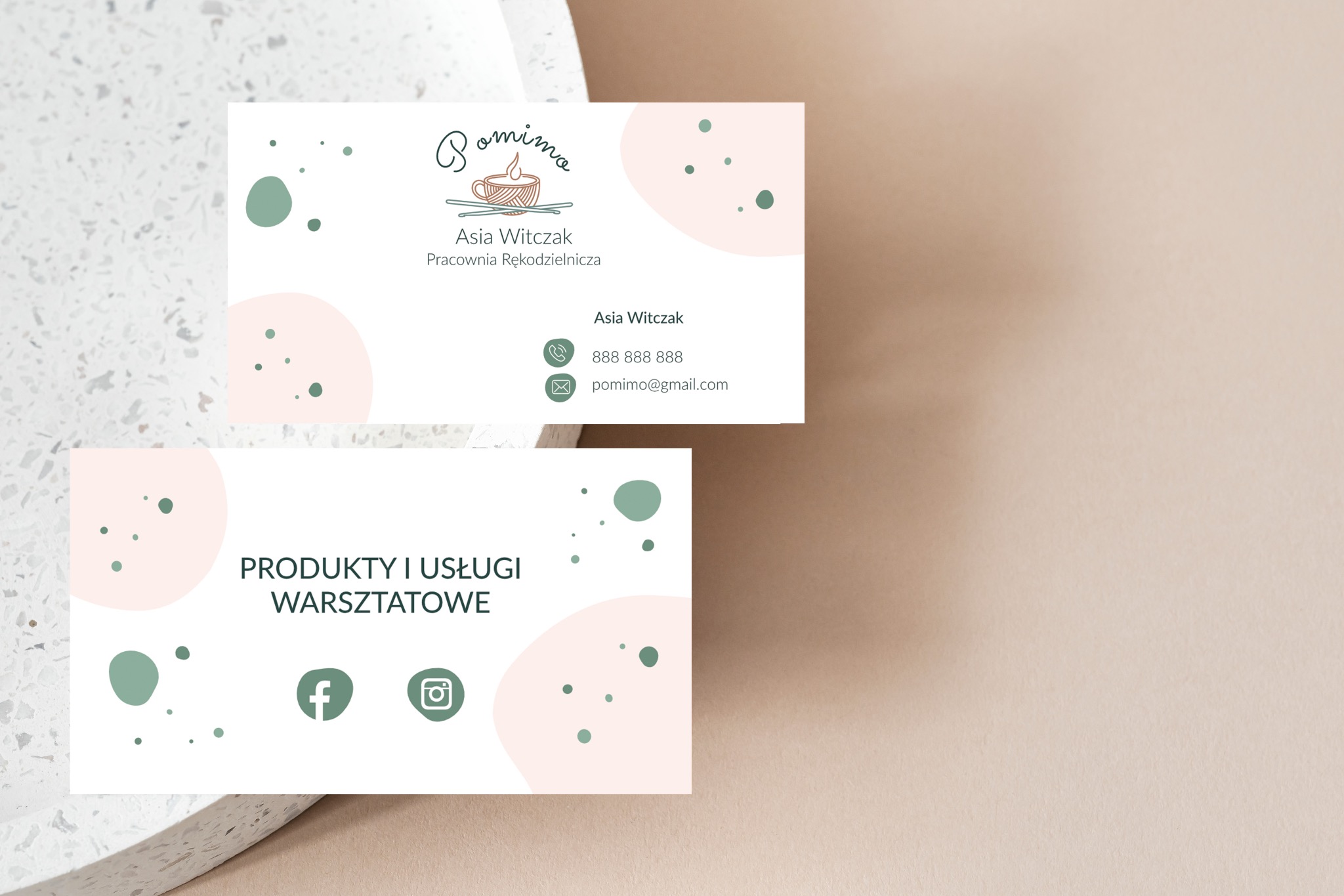 Dwie wizytówki z logo pracowni rękodzielniczej, w pastelowych odcieniach, leżące na jasnym tle z delikatną fakturą.