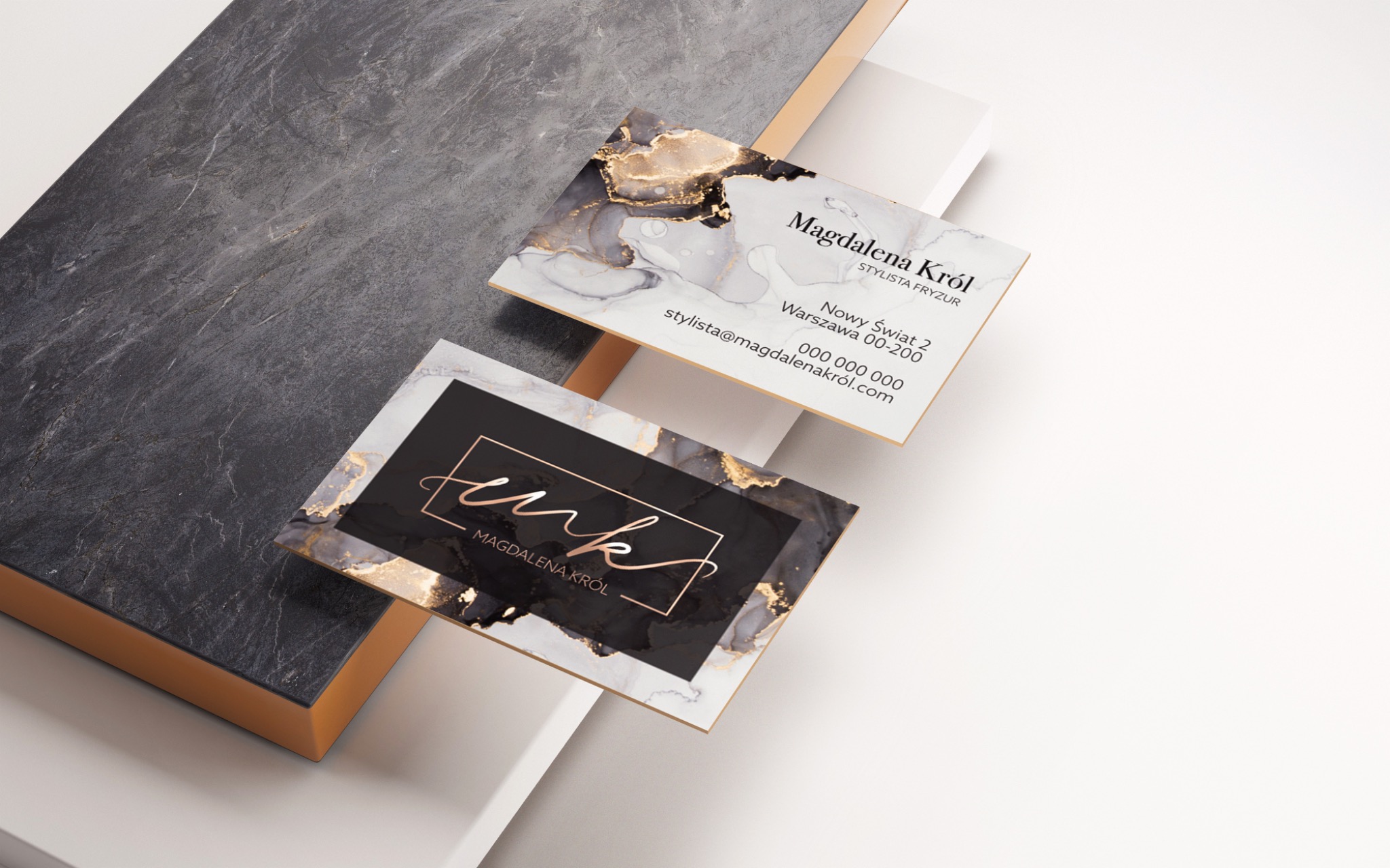 Dwie wizytówki z motywem marmuru i złotych akcentów, jedna z logo 'mk' w złotej ramce, druga z danymi kontaktowymi stylistki fryzur Magdaleny Król, ułożone na abstrakcyjnym tle w odcieniach...
