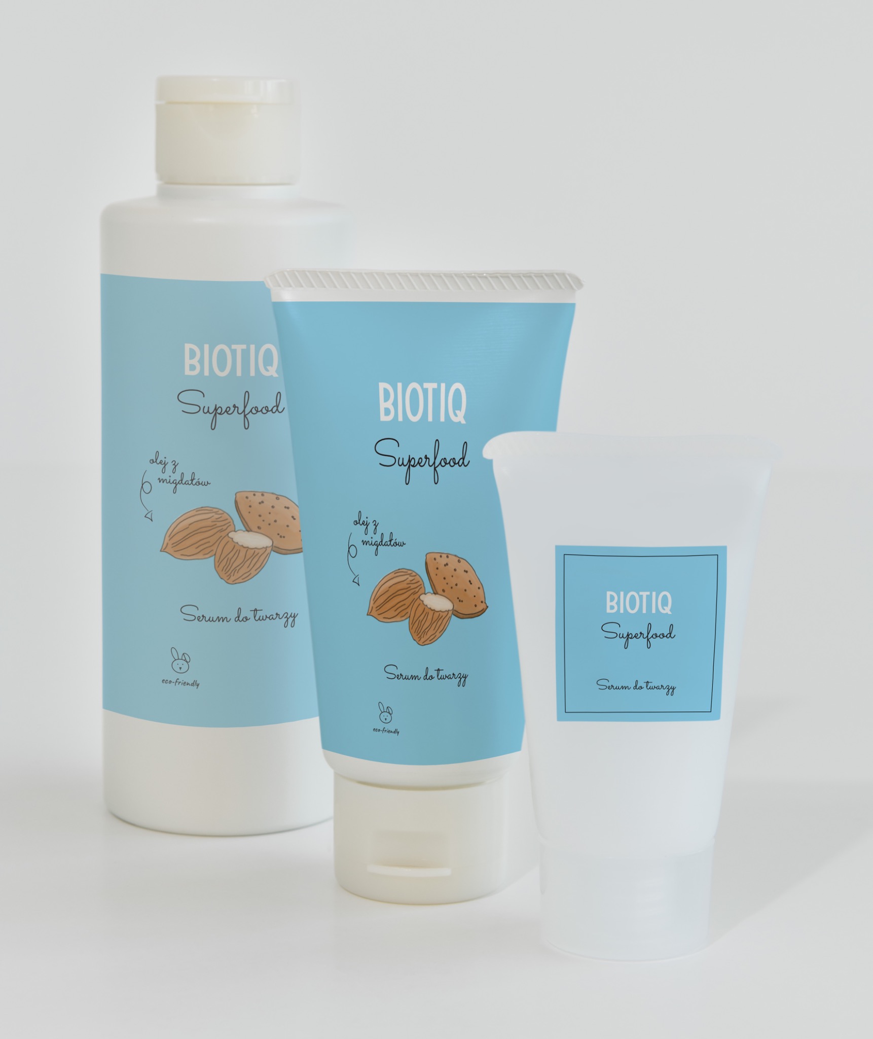 Trzy opakowania kosmetyków BiotIQ Superfood z motywem migdałów, prezentujące serum do twarzy w różnych formach: butelka, tuba i pojemnik.