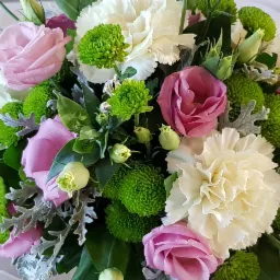 Dekoracja stołu z białych goździków, różowych róż i zielonych chryzantem kulistych, widelce po obu stronach, delikatna biała tkanina.