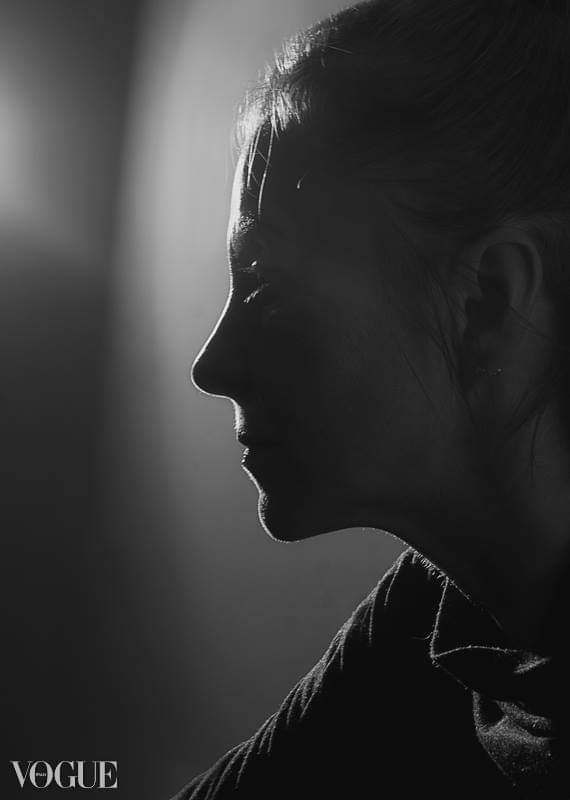 Czarno-biały portret profilowy kobiety, oświetlony od tyłu, z widocznym logo 'VOGUE' w lewym dolnym rogu.