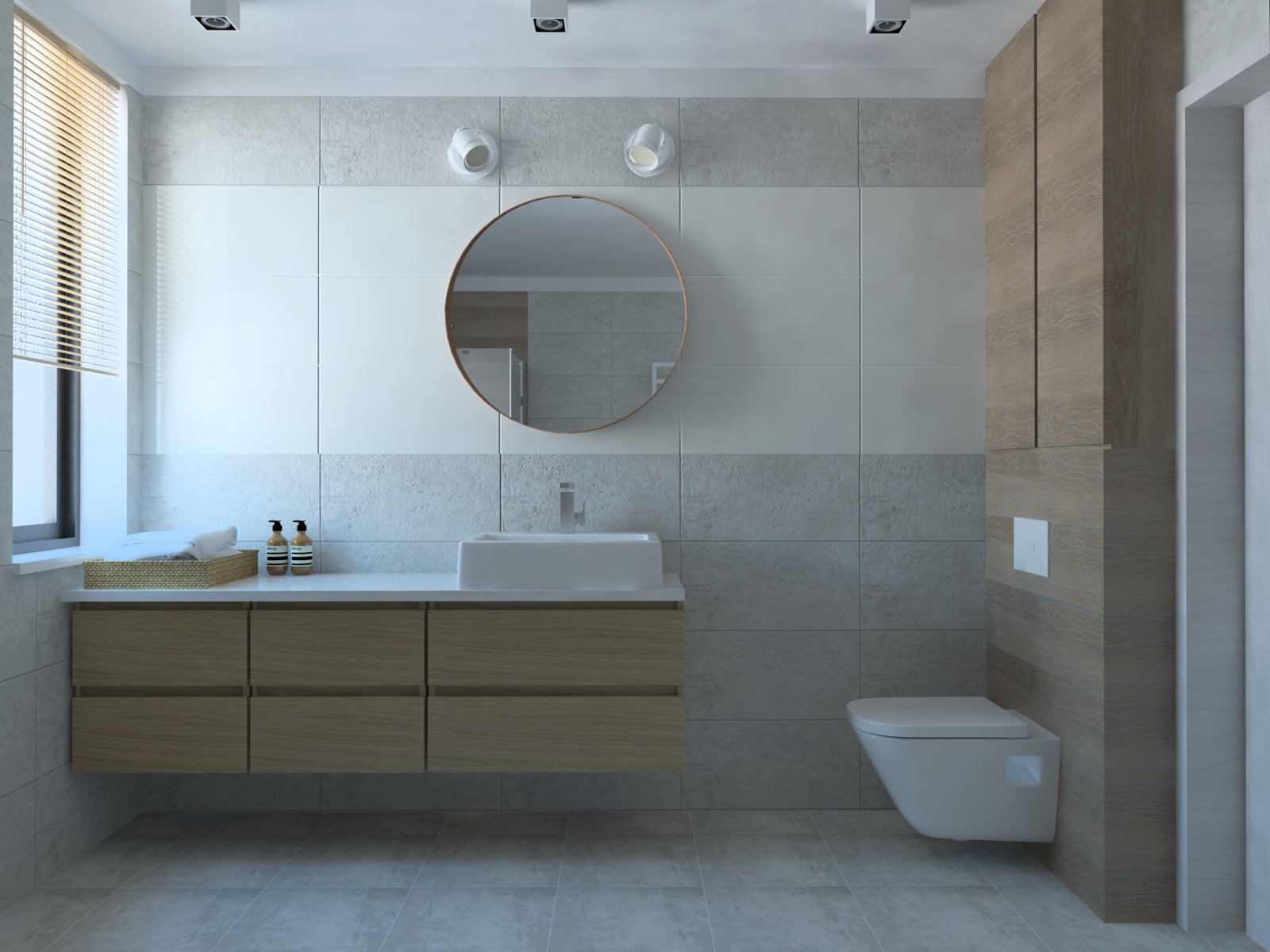 Nowoczesna łazienka w domu jednorodzinnym z drewnianymi akcentami: szafka pod umywalką z sześcioma szufladami, okrągłe lustro, podwieszana toaleta i płytki w odcieniach szarości i bieli.