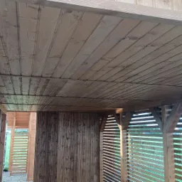 Zadaszenie tarasu z drewnianych desek, widok od spodu, z elementami konstrukcyjnymi i przesłonami z listew.