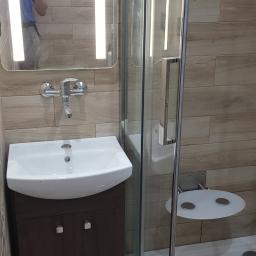 Max-Bud - Nowoczesna łazienka z kabiną prysznicową, umywalką z szafką w kolorze wenge, lustrem z oświetleniem LED i siedziskiem w kabinie prysznicowej, widoczne narzędzia na podłodze.