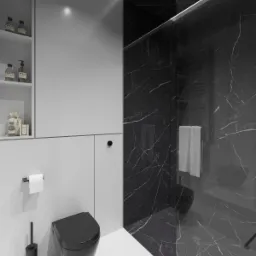 Minimalistyczna łazienka w odcieniach szarości i czerni z kabiną prysznicową wyłożoną marmurem, podwieszaną toaletą i półkami z kosmetykami.