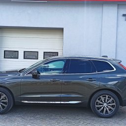 EXTREME DESIGN - Szary SUV Volvo XC60 zaparkowany przed budynkiem z napisem 'TUNING'. Widoczne ciemne szyby i felgi aluminiowe. Ujęcie z boku, na pierwszym planie kostka brukowa.