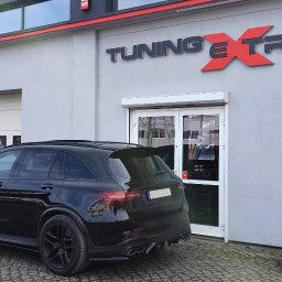 EXTREME DESIGN - Czarny SUV Mercedes-Benz zaparkowany przed budynkiem firmy Tuning Extreme. Widoczne logo firmy nad wejściem. Detal: czarne felgi i przyciemnione szyby.