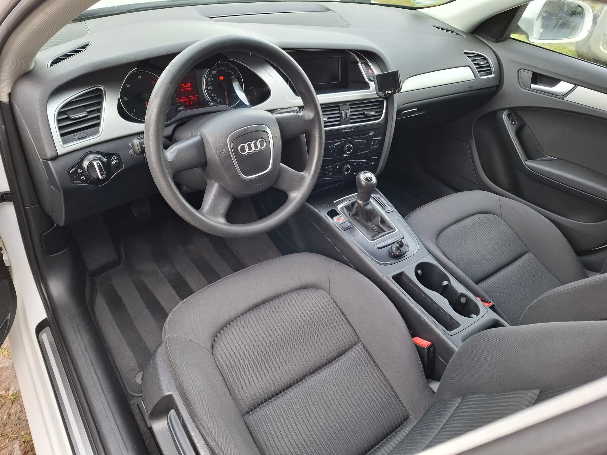 Wnętrze Audi A4 z czarną tapicerką: deska rozdzielcza, kierownica z logo Audi, fotele i dywaniki po czyszczeniu. Widoczny kokpit i konsola środkowa.