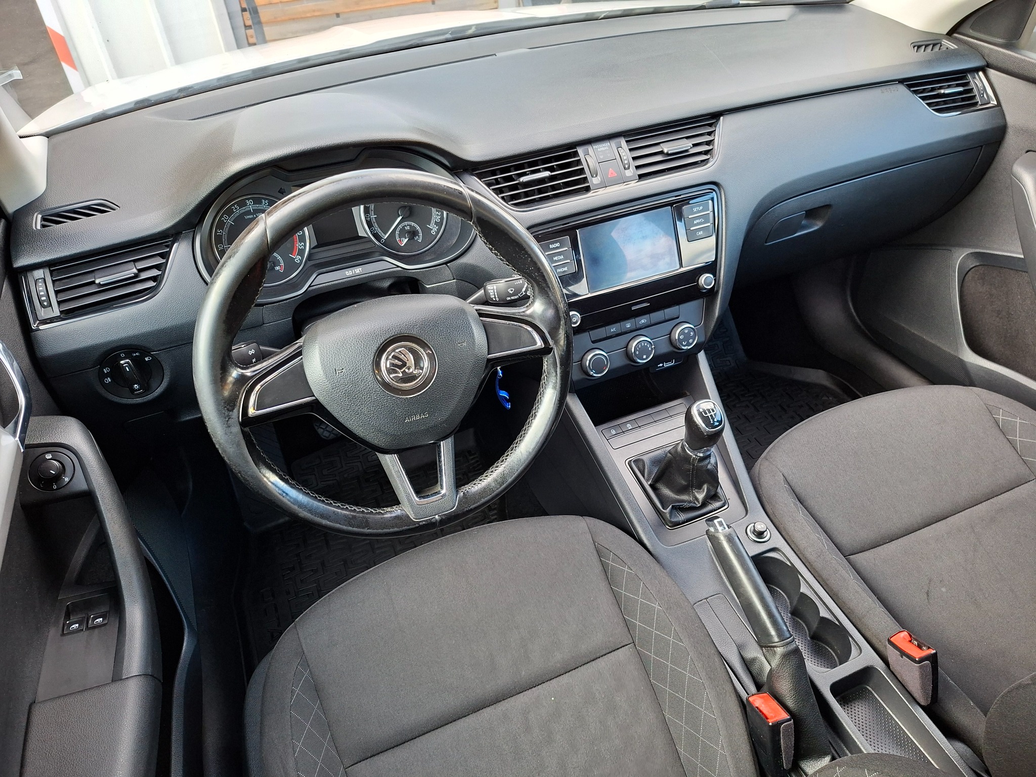 Wnętrze samochodu marki Skoda Octavia z widocznymi czarnymi fotelami, kierownicą i deską rozdzielczą. Czyste, zadbane wnętrze pojazdu.