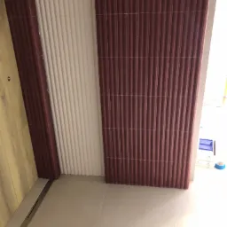 Ukończona łazienka z brązowymi i białymi panelami ściennymi o prążkowanej strukturze, szara podłoga z odpływem liniowym, widok z góry.