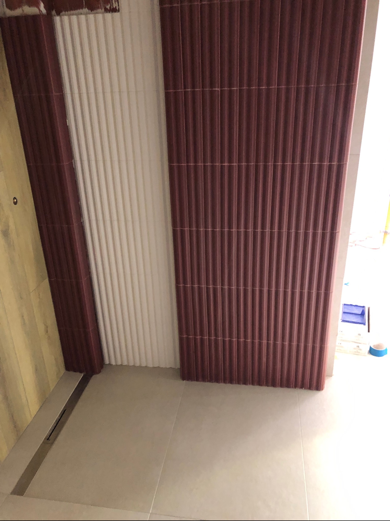 Ukończona łazienka z brązowymi i białymi panelami ściennymi o prążkowanej strukturze, szara podłoga z odpływem liniowym, widok z góry.