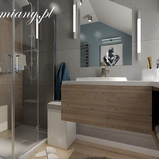 Nowoczesna łazienka z kabiną prysznicową, drewnianą szafką pod umywalką, lustrem z oświetleniem LED i szarymi płytkami na ścianach. W tle widoczny obraz na ścianie.