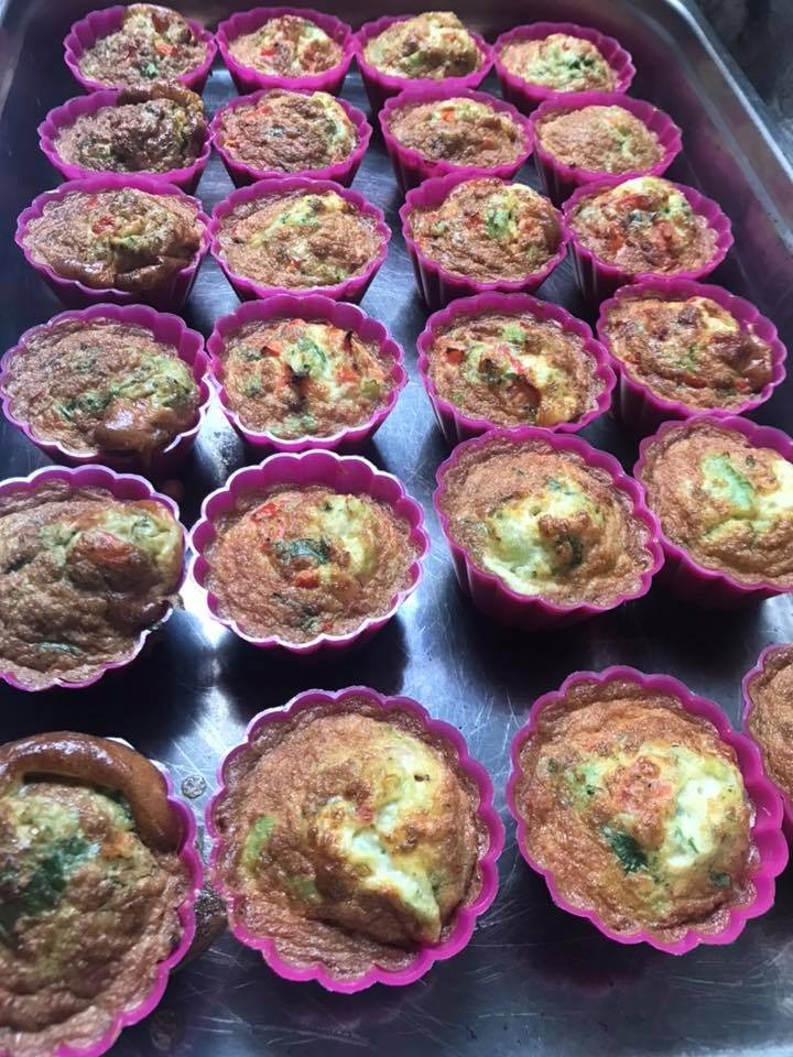 Taca z muffinkami wytrawnymi w różowych silikonowych foremkach, widoczne kawałki warzyw, oświetlenie dzienne.