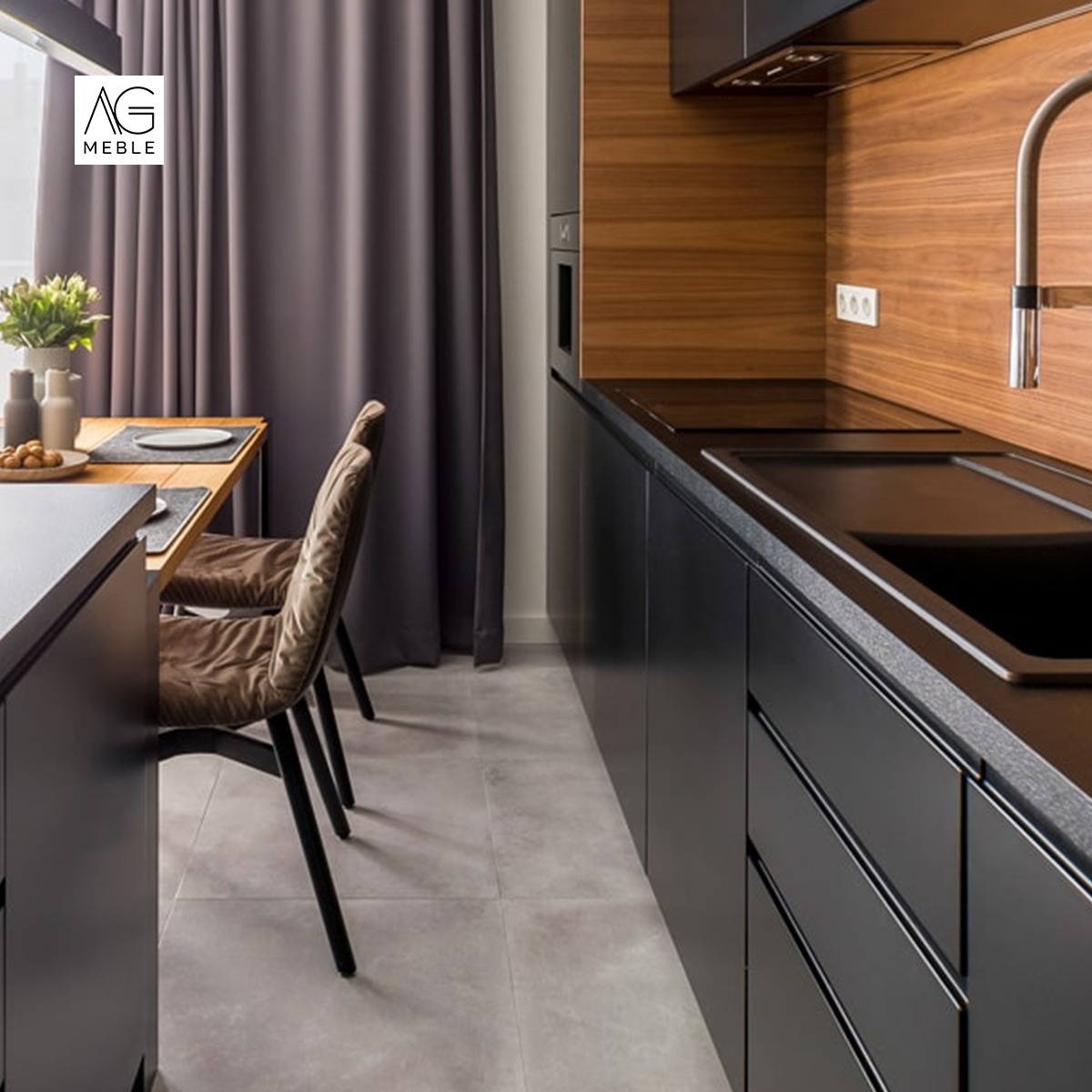 Nowoczesna kuchnia z czarnymi szafkami, drewnianym blatem i panelem ściennym, oraz stołem z krzesłami obok zasłoniętego okna.