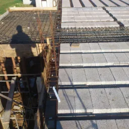 Wykonywanie stropu Teriva z szalunkiem w Złotoryi, widoczny cień osoby na konstrukcji.