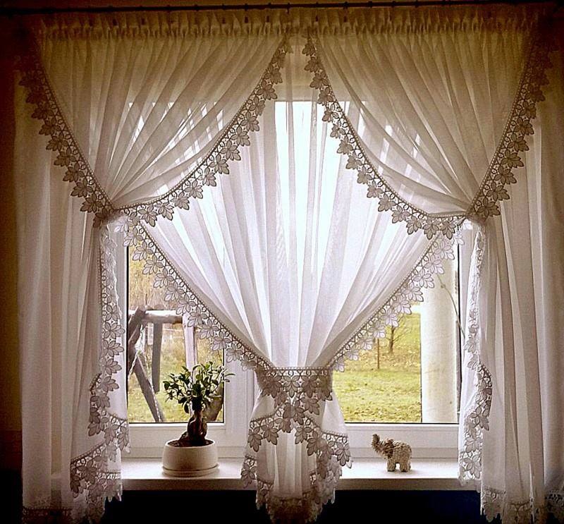 Okno udekorowane białymi, woalowymi zasłonami z koronkowym wykończeniem, na parapecie bonsai i figurka słonia.