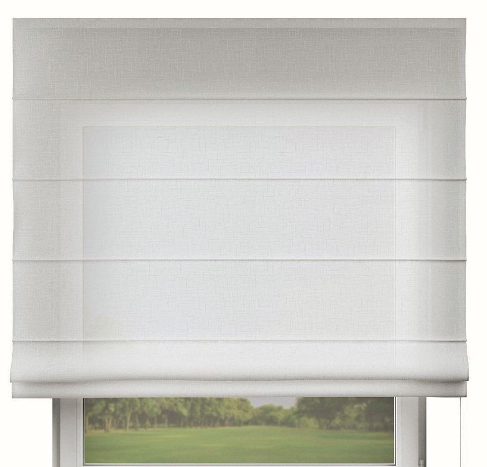 Biała, rzymska roleta tekstylna zamontowana w oknie z widokiem na zielony krajobraz.