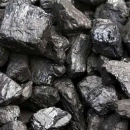 Kupa błyszczącego, czarnego węgla kamiennego o nieregularnych kształtach, ułożona w zwartą pryzmę, z widocznymi refleksami światła na powierzchni brył.