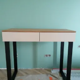 Biurko z szufladami na stalowych nogach.