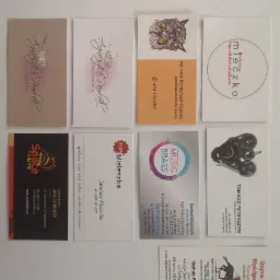 Kolekcja różnorodnych wizytówek, prezentujących różne style graficzne, od minimalistycznych po bogato ilustrowane, ułożonych na białym tle.