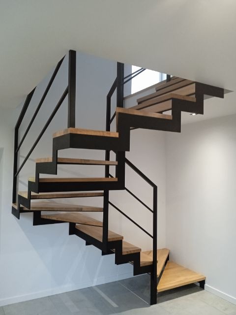 Nowoczesne schody wewnętrzne z drewnianymi stopniami i czarną metalową konstrukcją, minimalistyczny design, jasne wnętrze.