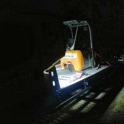 Daniels Daniel Mokijewski - Transport wózka widłowego STILL na platformie transportowej w nocy, zabezpieczony pasami transportowymi.