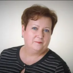 Portret kobiety o krótkich brązowych włosach i niebieskich oczach, ubrana w czarno-szarą bluzkę w paski, na jasnym tle.