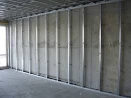 Stelaż z profili stalowych pod płyty gipsowo-kartonowe, widoczne mocowania do sufitu i podłogi, surowy stan przed montażem okładziny, okno w tle.