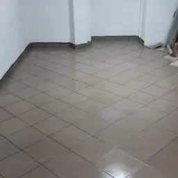 Wykończone wnętrze w Oławie z nową, błyszczącą podłogą z płytek ułożonych w karo, białe ściany i sklepione sufity, małe okno w górnej części ściany.