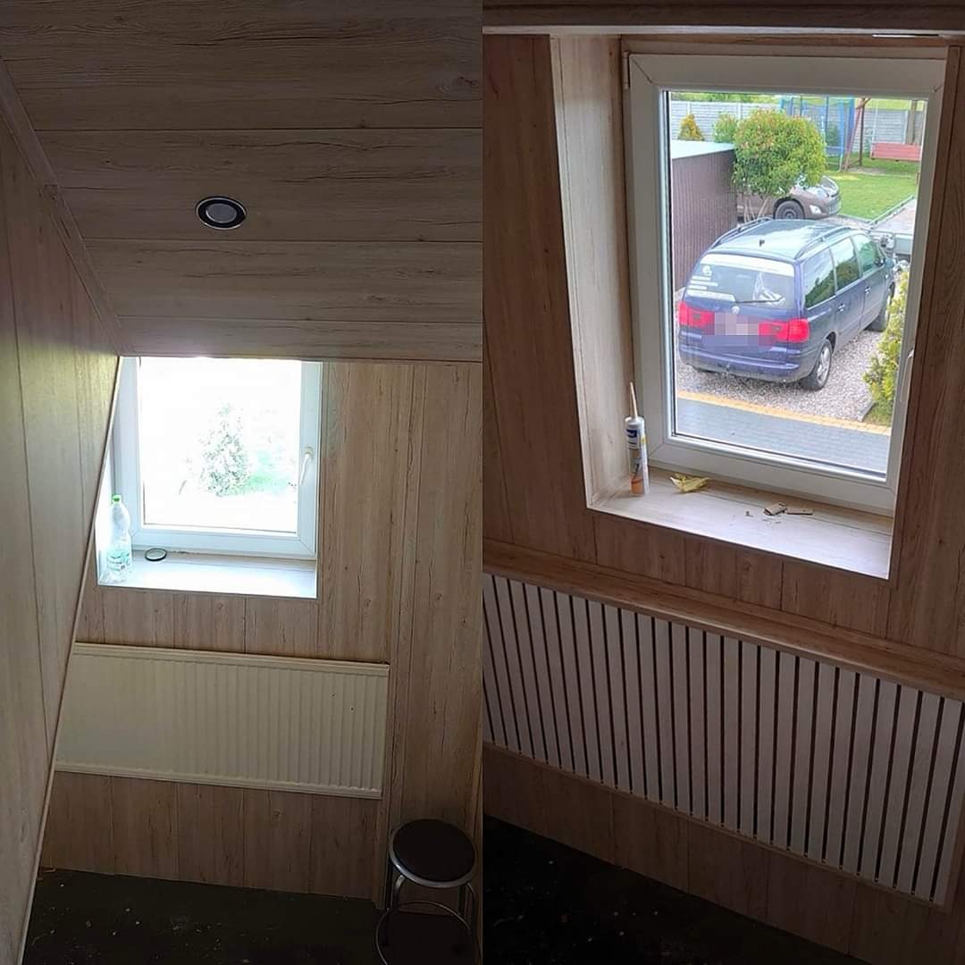 Klatka schodowa wykończona panelami ściennymi imitującymi drewno, z widocznym grzejnikiem i oknem z widokiem na podjazd z zaparkowanym samochodem.