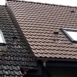 Częściowo umyty dach z brązowej dachówki w Książu Wielkopolskim; widoczna różnica w kolorze między czystą i brudną częścią dachu, z kominkiem wentylacyjnym i oknem dachowym.