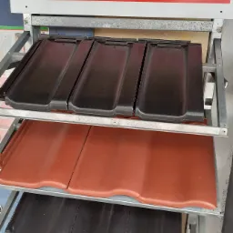 Ekspozycja dachówek marki Nelskamp w sklepie budowlanym, prezentacja różnych kolorów i modeli na metalowym regale.