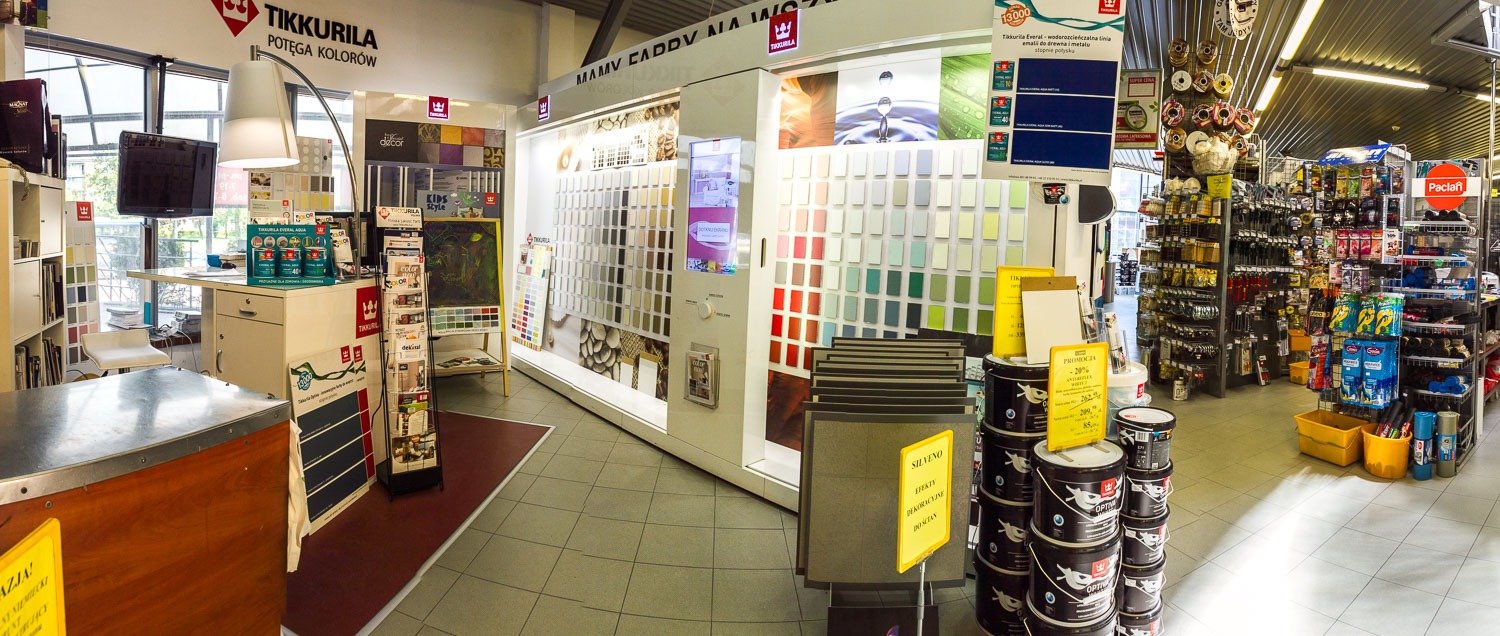Wnętrze sklepu z materiałami budowlanymi, ekspozycja farb Tikkurila, wzorniki kolorów, pędzle i inne akcesoria malarskie na półkach.