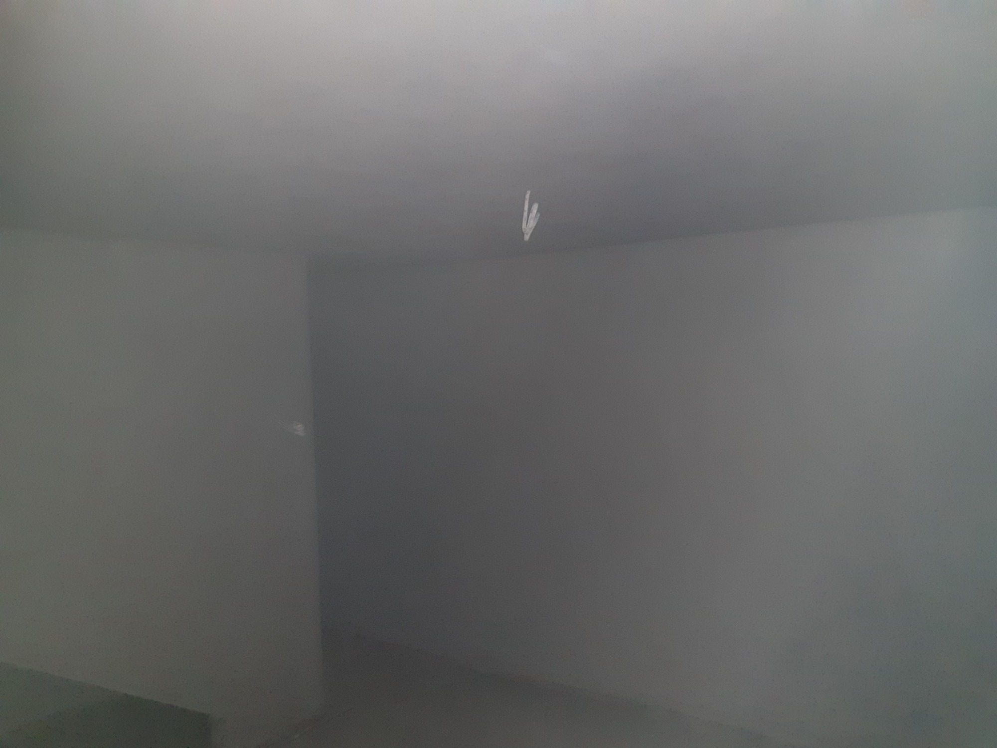 Szare, jednolite ściany i sufit po nałożeniu tynku, widoczny niewielki niedoskonałość na suficie.