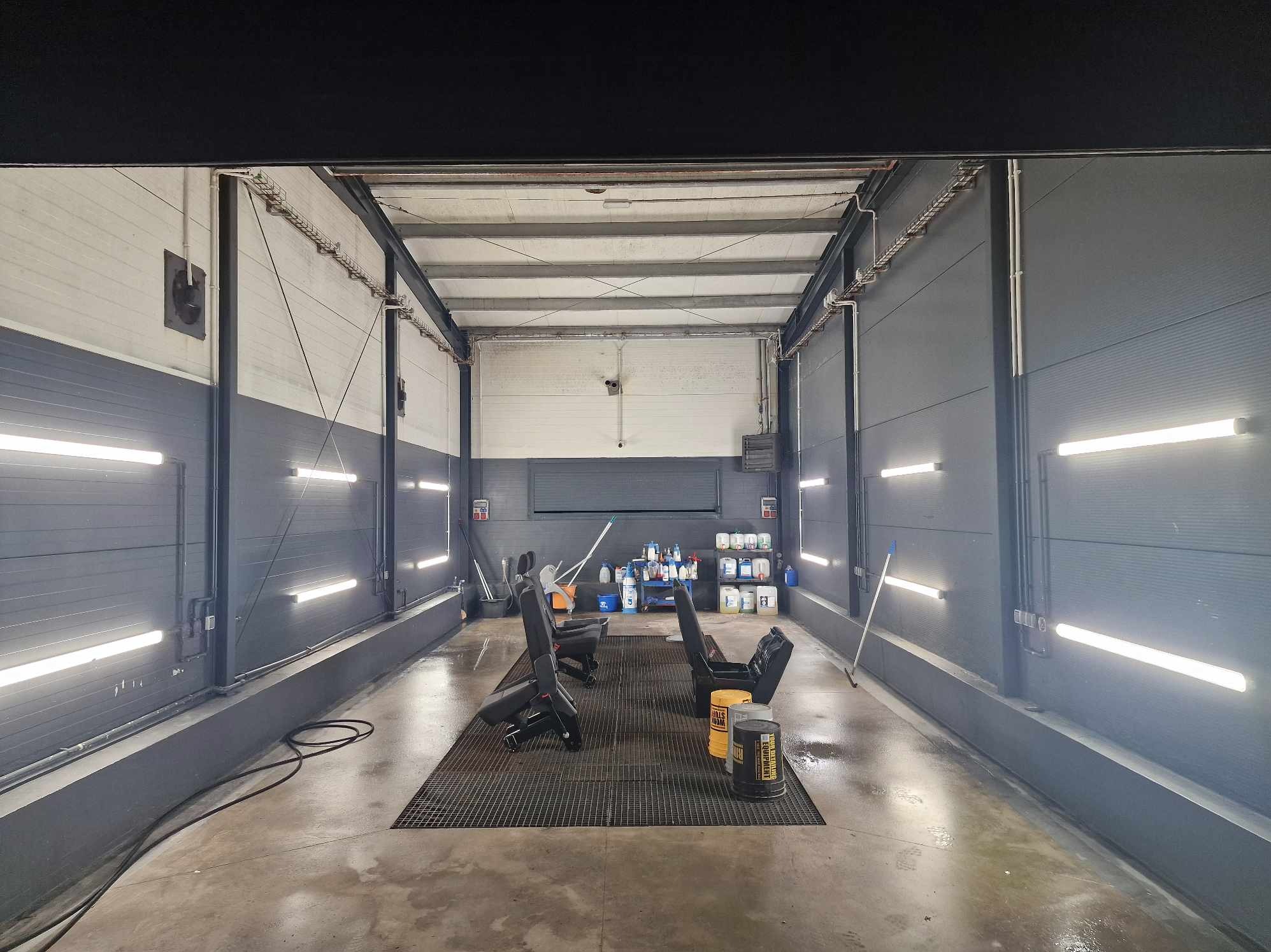Wnętrze hali z oświetleniem LED, kratą podłogową i sprzętem do czyszczenia tapicerki samochodowej w Brenno.